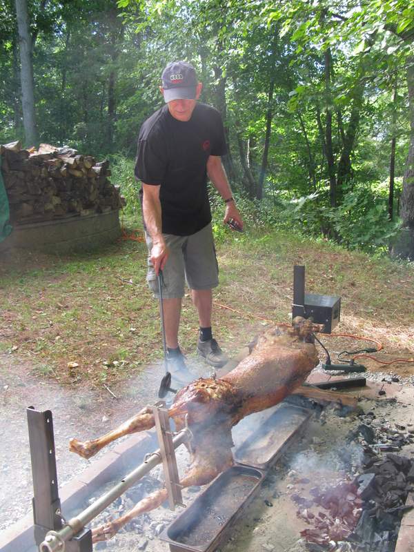 Pitmaster at work tending lamb on a spit