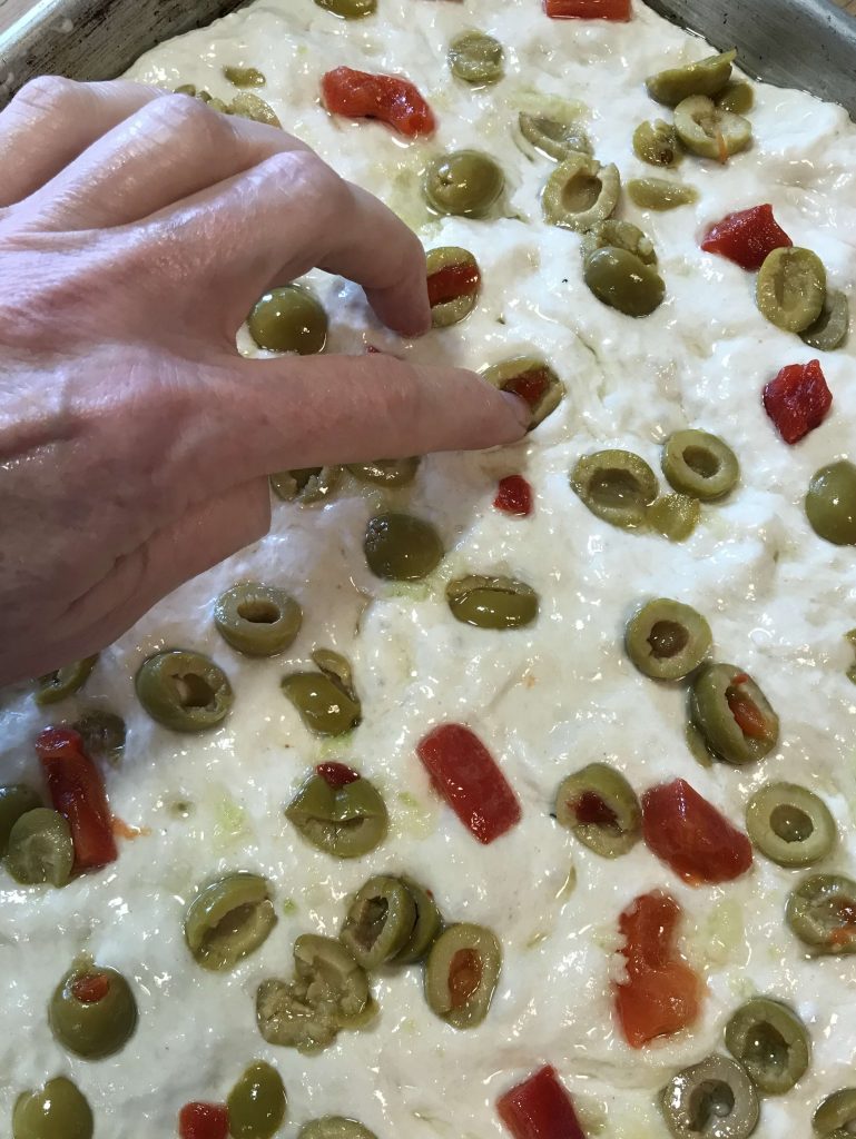 Placeing olives on focaccia dough