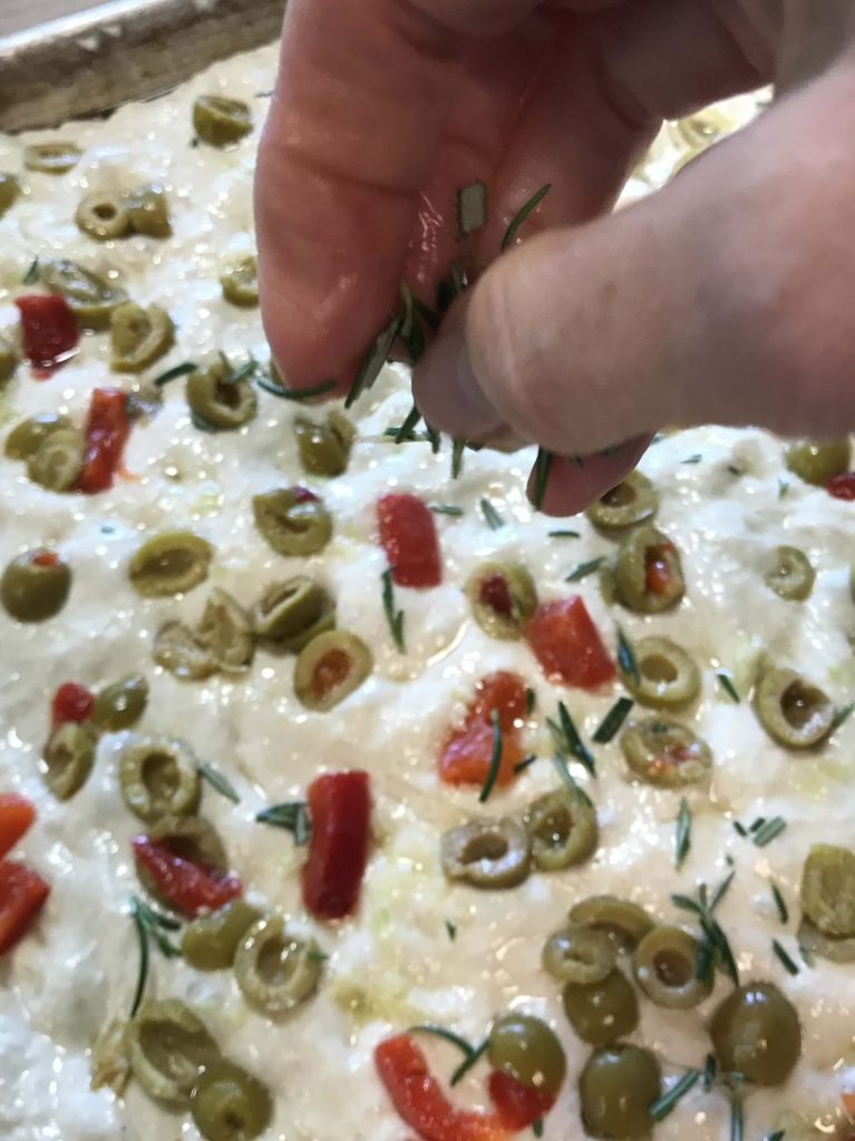 Sprinkling Olive Rosemary Focaccia with rosemary
