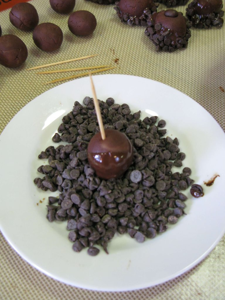 Dipping chocolate marzipan truffles into chocolate chips