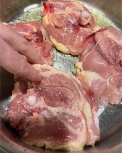 Placing chicken in pan for Chicken Curry with Green Almonds, Carrots and Turnips